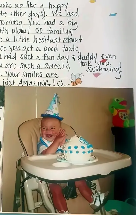 A one-year-old in a party hat claps in a high chair in front of a first birthday cake, below a handwritten birthday note